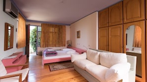 A bedroom with a bed, a sofa, wooden cabinets, and a window with curtains.
