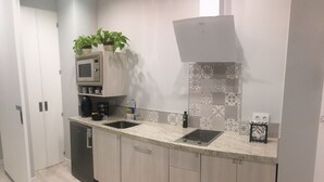 Una cocina moderna con dos fregaderos, un microondas, una cafetera y un lavavajillas. Hay plantas en macetas sobre la encimera y un salpicadero de azulejos.