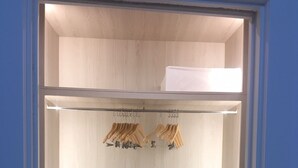 Un vestidor con paredes de madera, una barra para colgar ropa y un estante.