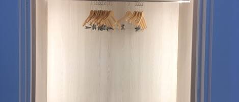 A walk-in closet with wooden walls, a hanging rod, and a shelf.