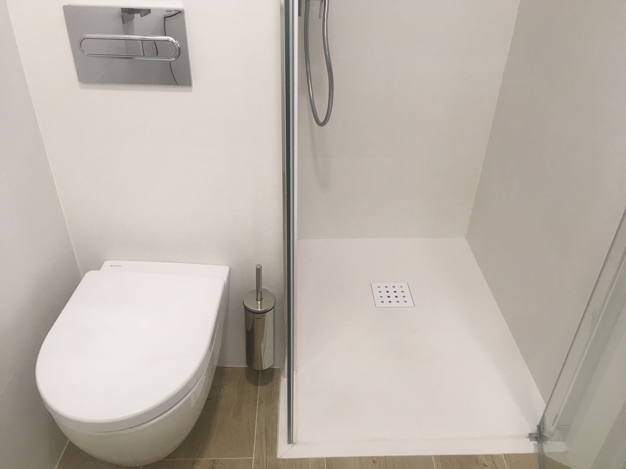 Une salle de bain moderne équipée de toilettes, d’une douche avec une porte en verre et d’une barre d’appui en métal.