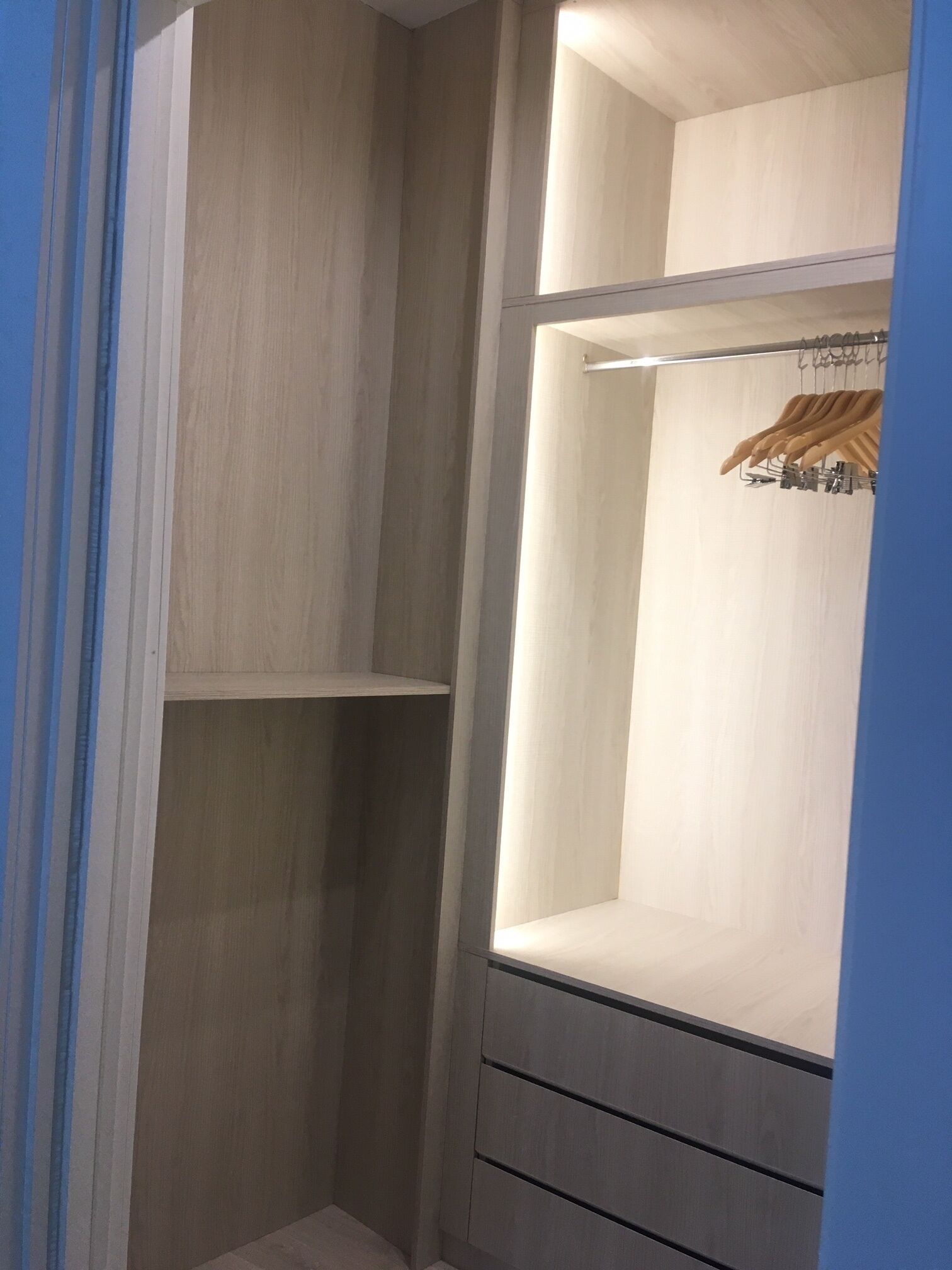 Ein begehbarer Kleiderschrank mit offenen Regalen und einer Kleiderstange.