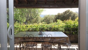 An outdoor patio with a table and chairs, surrounded by a metal railing and lush greenery. - Villa Provencale Face AU Luberon (Cabrières-d'Avignon)