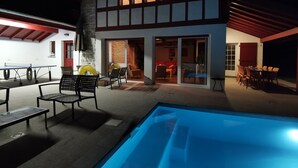 Ein modernes Haus mit Swimmingpool, Außenbereich und einer roten Tür.