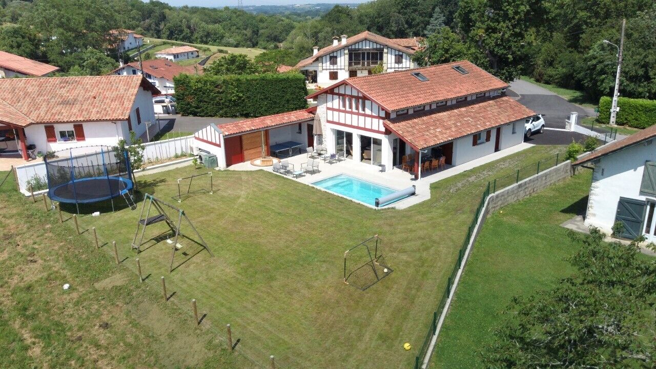 A large house with a swimming pool, a trampoline, and a tennis court.