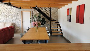 Ein moderner Essbereich mit Holztisch, Stühlen, einer roten Couch, einer Treppe und einer Steinwand.
