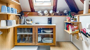 Et lille køkken med træskabe, komfur og et vindue over vasken.