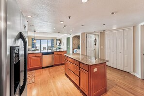 Una cocina con armarios de madera, encimera de granito y refrigerador de acero inoxidable.