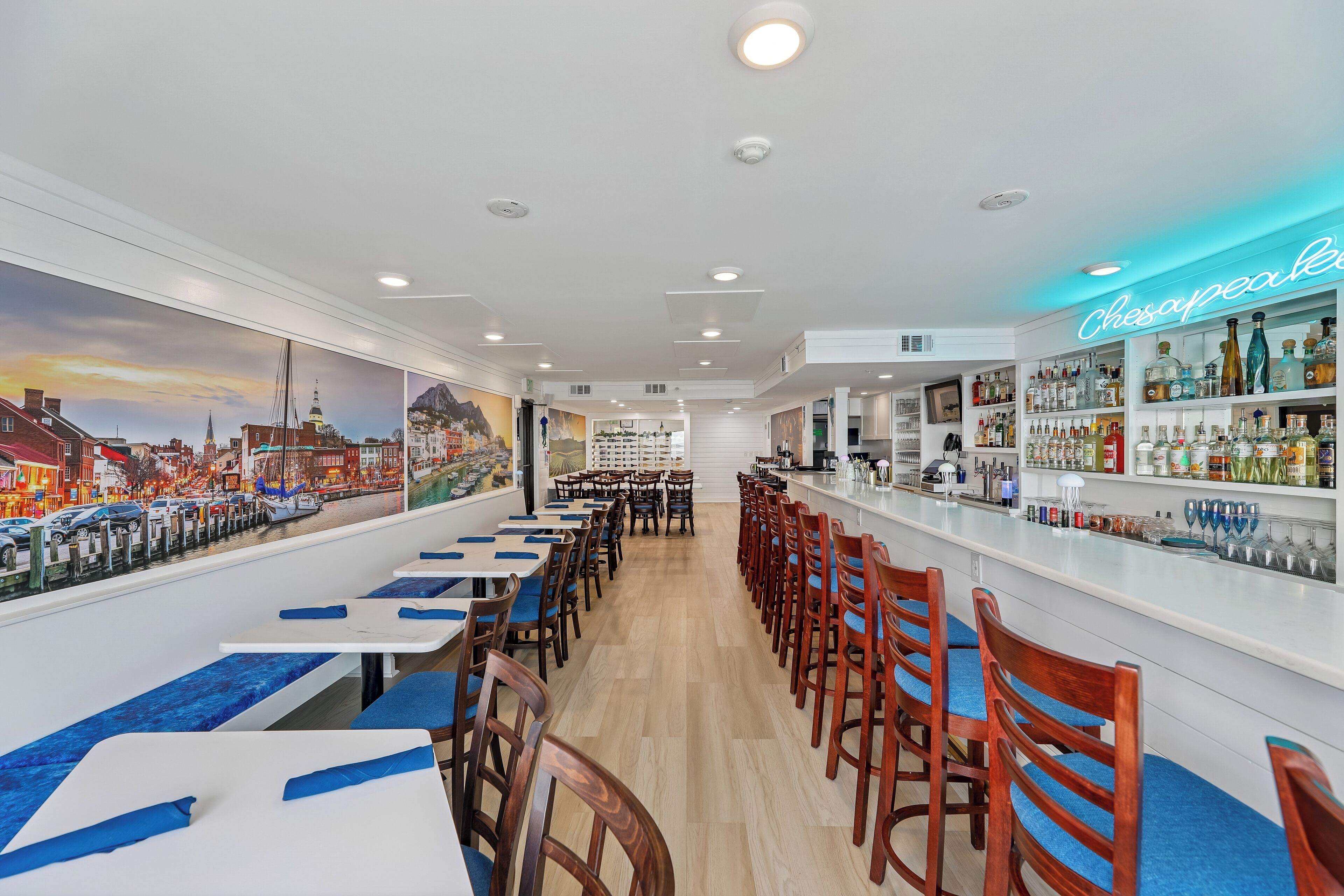 A bar area with a neon sign reading "Chesapeake Bay" and a mural of a cityscape on the wall.