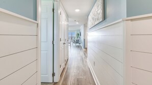 A hallway with a light-colored floor, white walls, and a door on the left. - This absolutely beautiful 3 bedroom, 2 bath condo completely remodeled into a stunning beach home. (Ocean City)