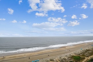 A beach with a clear sky, sandy shore, and a few people. - XPLORIE ACTIVITIES & LINENS INCLUDED*! THE PLAZA - Beautiful 2BR/open Den Condo on the Oceanfront! (Ocean City)