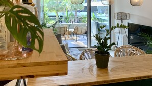A modern kitchen with wooden countertops, hanging pendant lights, and a view of the outdoor patio area. - Haven of peace with infinity pool overlooking the sea (Villeneuve-Loubet)