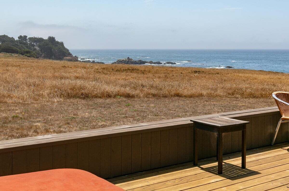 Una terraza con vista al océano, una silla y una pequeña mesa.