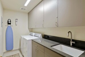 A compact kitchen with a built-in sink, a washing machine, and a drying rack.
