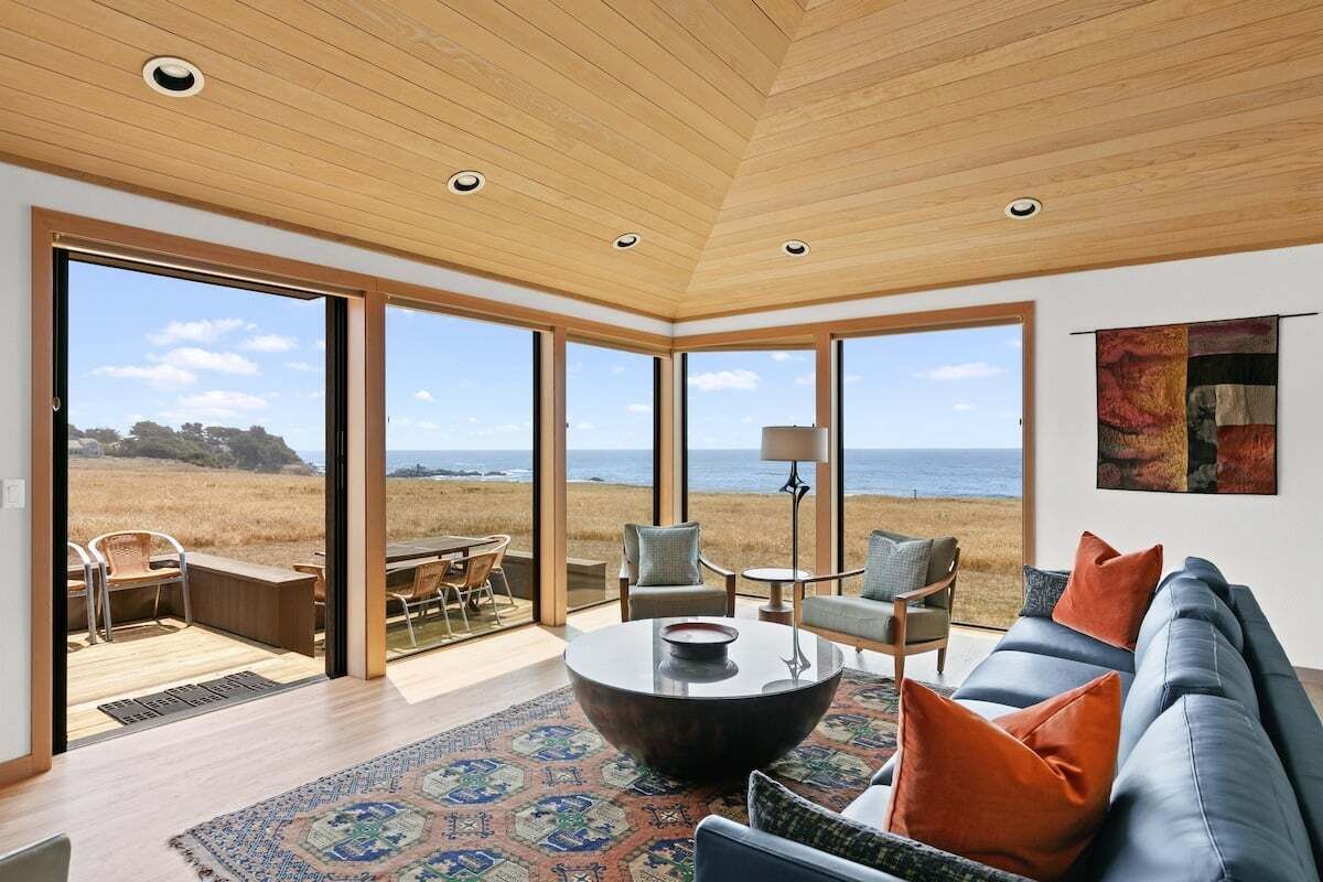 A modern living room with a large window, a round coffee table, and a sofa with cushions.