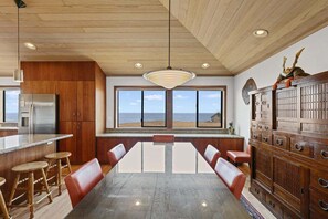 A modern kitchen with a large island, wooden cabinets, and a view of the beach. - Kyuka | Asian-Inspired Coastal Retreat (Sea Ranch)