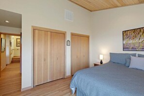 A bedroom with a bed, wooden wardrobe, a painting, and a nightstand. - Kyuka | Asian-Inspired Coastal Retreat (Sea Ranch)