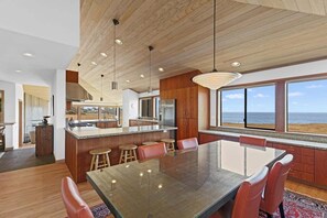 A modern kitchen with a large island, wooden ceiling, and a view of the ocean. - Kyuka | Asian-Inspired Coastal Retreat (Sea Ranch)
