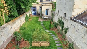 A well-maintained garden with a wooden planter, stone steps, and a blue door. - HISTOIRE DE LOIRE - La Maison (Saumur)