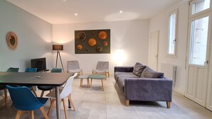 A modern living room with a dining area, a sofa, a coffee table, and a TV. - HISTOIRE DE LOIRE - La Maison (Saumur)