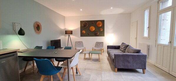 A modern living room with a dining area, a sofa, a coffee table, and a TV. - HISTOIRE DE LOIRE - La Maison (Saumur)