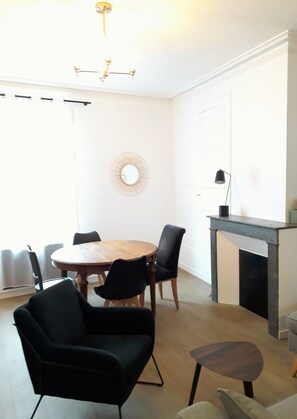 Un comedor con una mesa redonda de madera, sillas negras, una mesita auxiliar y una chimenea.