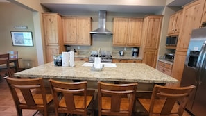 A kitchen with wooden cabinets, a granite countertop, a stainless steel range hood, and a built-in oven.