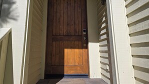 A wooden door with a small porch leading to a house with siding. - Snowcreek Resort Vacation Rental 1135 (Mammoth Lakes)