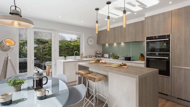 Een moderne keuken met een centraal eiland, barkrukken, een eettafel met stoelen en uitzicht op de omgeving.