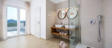 A modern bathroom with a glass shower enclosure, two sinks, and a large mirror.