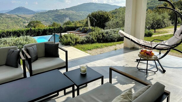 Una terraza con mobiliario exterior, piscina y vistas a las montañas.