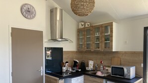 Una cocina compacta con lavavajillas, microondas, armarios de madera y una campana extractora de acero inoxidable.