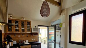 Una cocina moderna con armarios de madera, microondas integrado y un comedor con mesa y sillas.
