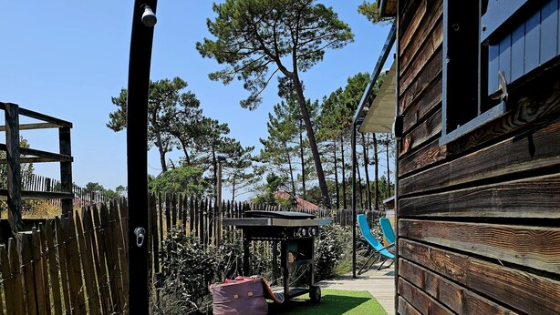 Una terraza de madera que lleva a una casa con patio cercado y un tobogán.