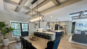 A spacious kitchen with a central island, modern appliances, and a dining area with a large wooden table and chairs. - Luxury Property: Private Pool, Hot Tub, Fire Pit and Close to Lake Sunsets (Fennville)