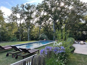 Une piscine rectangulaire entourée d’une terrasse en bois avec des chaises longues.