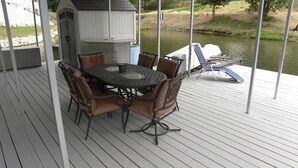 A covered outdoor deck with a round table and chairs, a grill, and a view of a lake. - Lake front home, 10mm, dock, only steps to the water, close to Franky & Louies (Sunrise Beach)