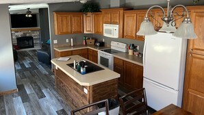 A modern kitchen with wooden cabinets, a built-in island, a microwave, and a refrigerator. - Lake front home, 10mm, dock, only steps to the water, close to Franky & Louies (Sunrise Beach)