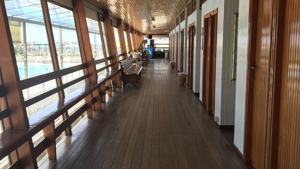 A corridor with wooden flooring and benches, large windows, and doors along one side. - Julia House (Viareggio)