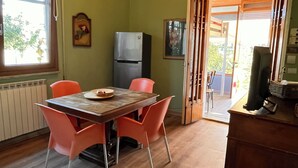 A dining area with a table and chairs, a refrigerator, and a wooden cabinet. - Julia House (Viareggio)