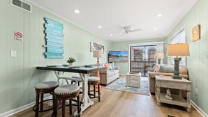 A well-lit living room with a dining area, a ceiling fan, and a view of the outside.