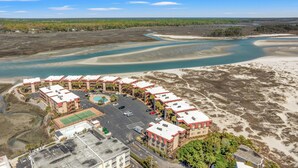 A coastal hotel with multiple buildings, a swimming pool, and a parking lot.