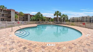 A swimming pool with a 3 FT depth marker, surrounded by a brick deck and a wooden fence.