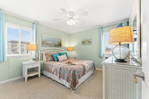 A bedroom with a bed, nightstands, a ceiling fan, and artwork on the walls.