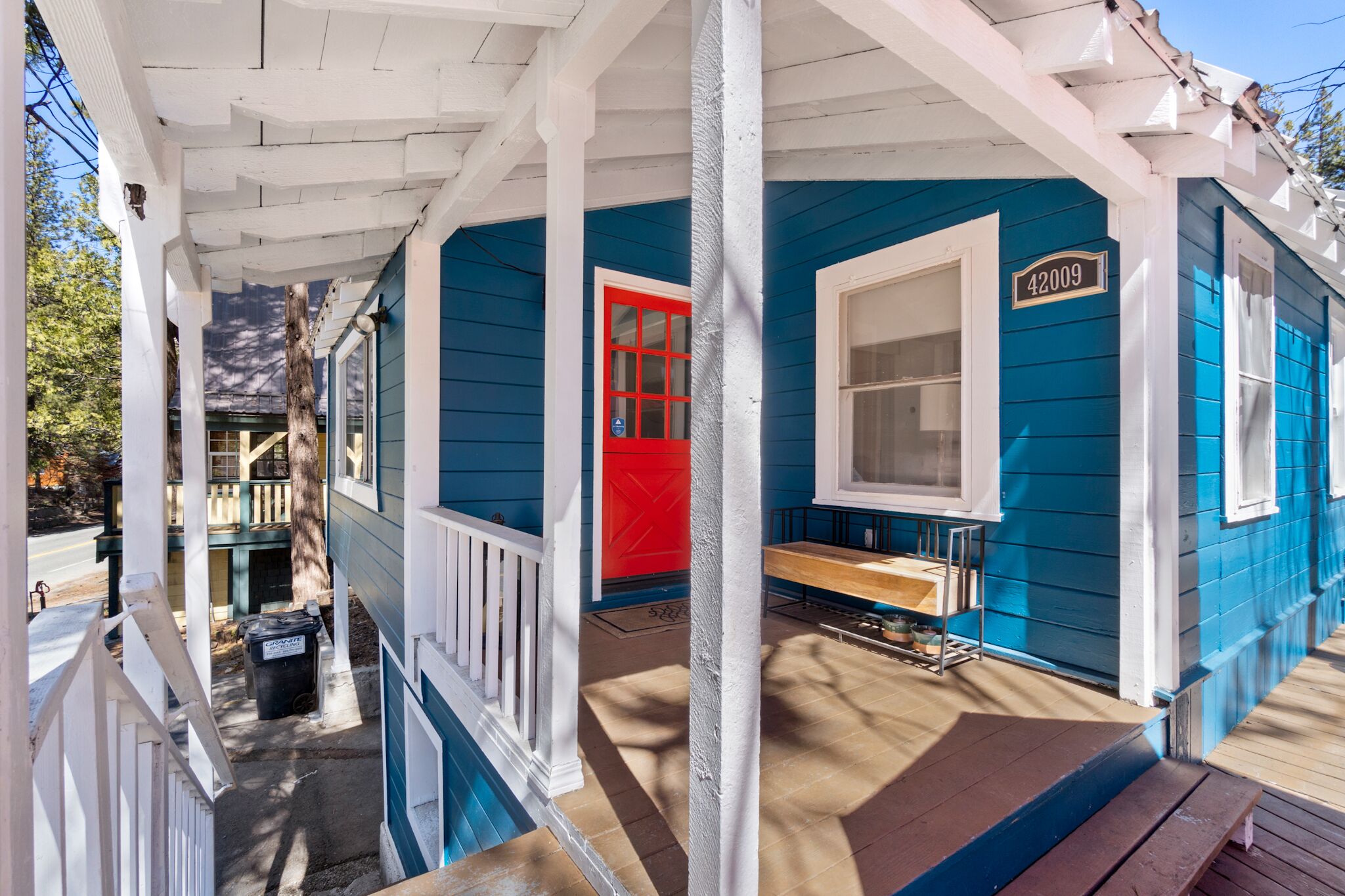 A blue house with a red door and a white porch.