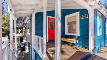 A blue house with a red door and a white porch.