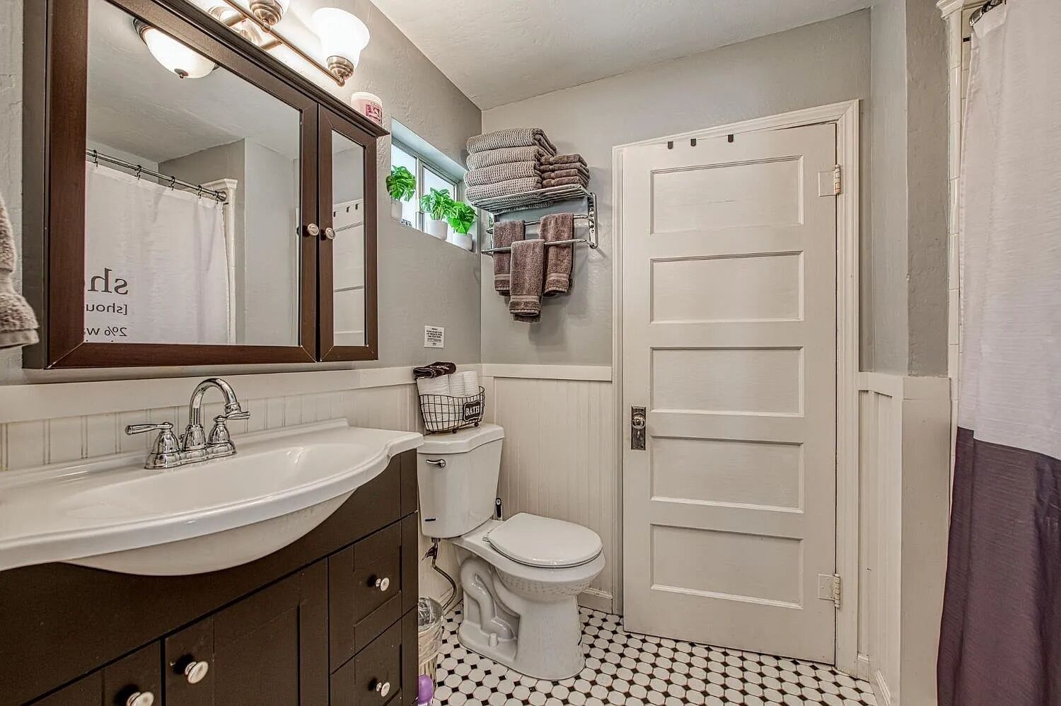 Une salle de bain avec un lavabo blanc, des toilettes, un miroir et une porte.