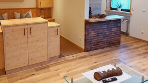 A compact kitchen with wooden cabinets, a brick accent wall, and a window with a view. - Cozy vacation apartment between Moselle and Rhine, near various dream loops and castles (Brodenbach)