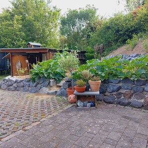 A garden area with a wooden structure, potted plants, and a stone wall.