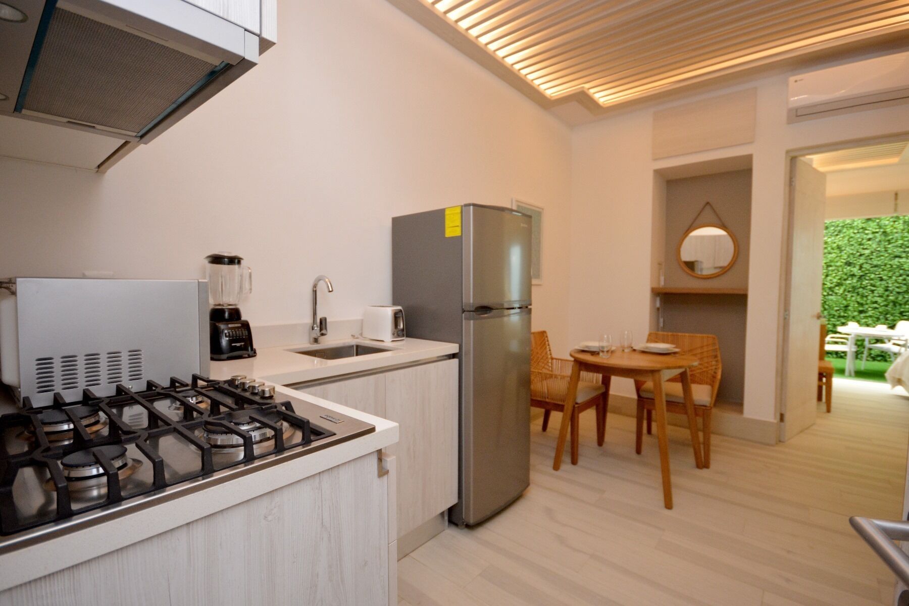 Una cucina moderna con piano cottura a gas, frigorifero, lavello e zona pranzo con tavolo e sedie.